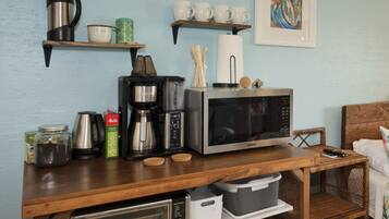 Una encimera de cocina con cafetera, microondas, tostadora y diversos utensilios de cocina.
