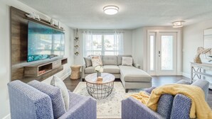 Ein modernes Wohnzimmer mit einem großen Flachbildfernseher, einem grauen Sofa und einem Couchtisch.