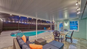 Ein überdachter Außenbereich mit Pool, Lounge-Möbeln und einem Esstisch mit Stühlen.
