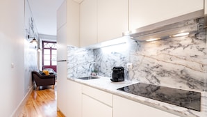 A modern kitchen with white cabinets, a marble backsplash, and a built-in stove. - VIVA Trindade Downtown (Porto)