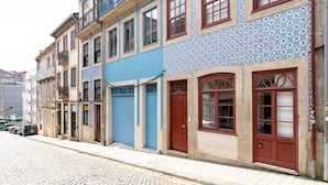 A cobblestone street lined with historic buildings featuring blue and red doors, balconies, and tiled facades. - VIVA Trindade Downtown (Porto)