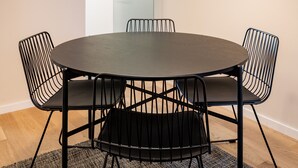 A round table with four black chairs, a hanging light fixture, and a wooden floor.