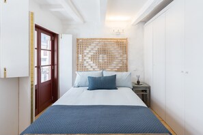 Une chambre à coucher avec un lit, une tête de lit en bois, une table de chevet et une porte.