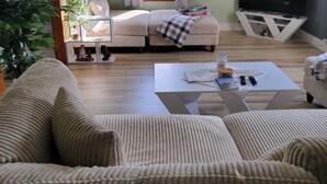 Un soggiorno con divano, tavolino, televisore e finestra con tende.