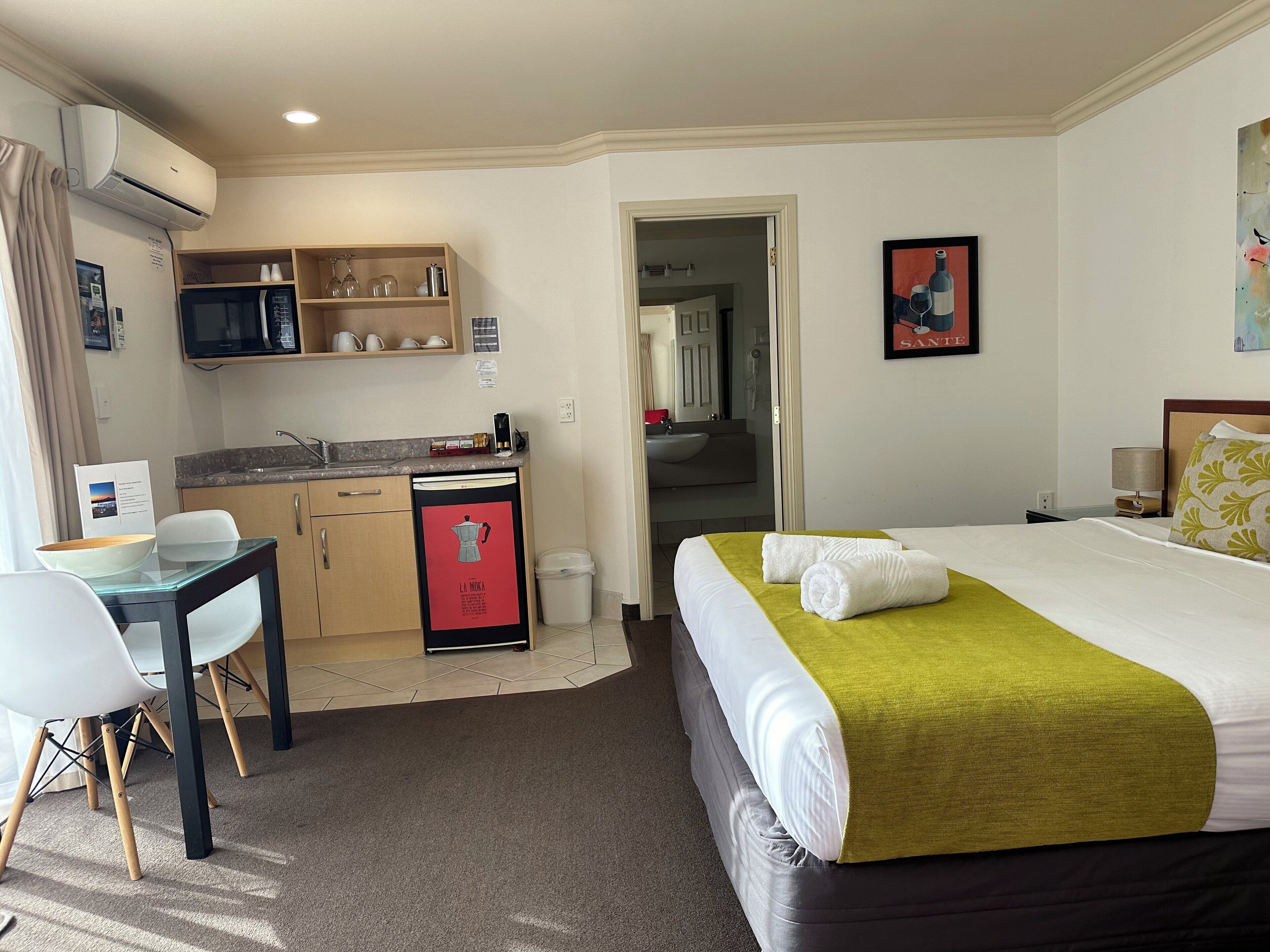 Une chambre d’hôtel comprenant un lit, un bureau, une kitchenette et une salle de bain.