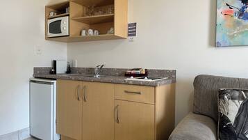 A compact kitchenette with a built-in microwave, a sink, and a small refrigerator.