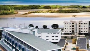 Un hotel costero con vista al océano y una montaña al fondo.