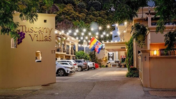 Entrada de un hotel con un letrero que dice "Tuscany Villas" y una bandera.