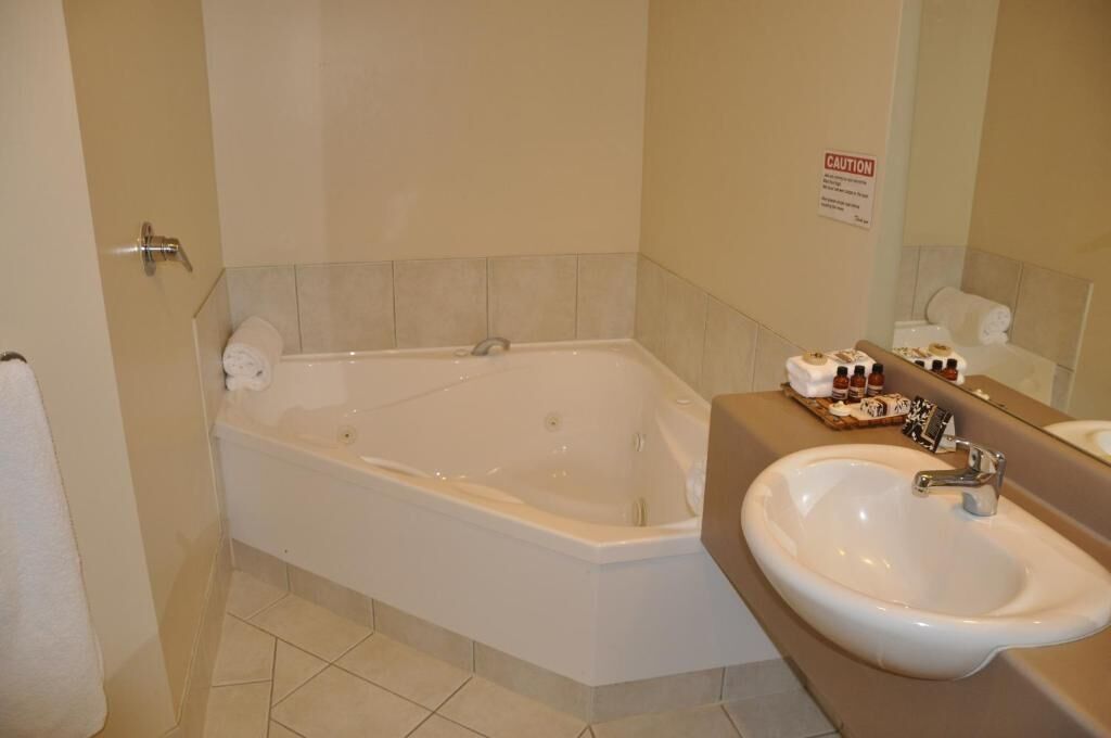 A bathroom with a bathtub, a sink, and a caution sign on the wall.