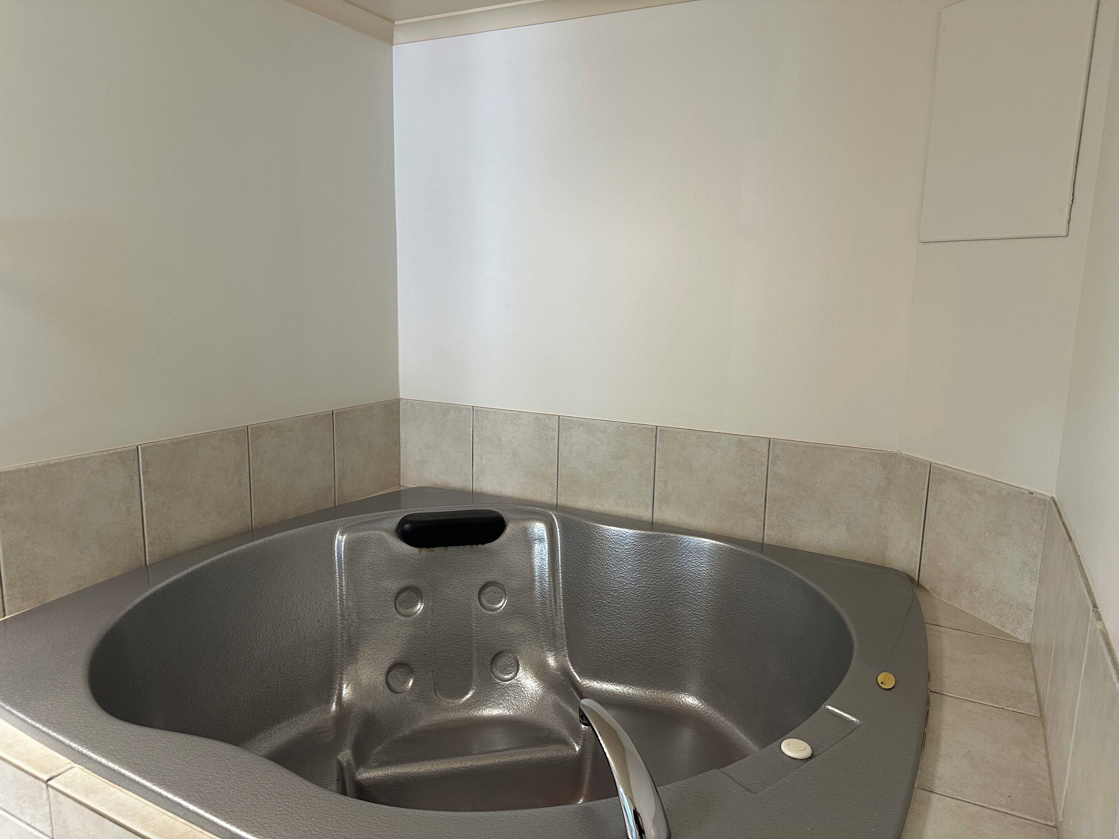 Une baignoire de spa dotée d’un siège intégré et de commandes, entourée de carreaux de couleur beige.