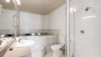 A modern bathroom with a sink, toilet, and glass-enclosed shower.