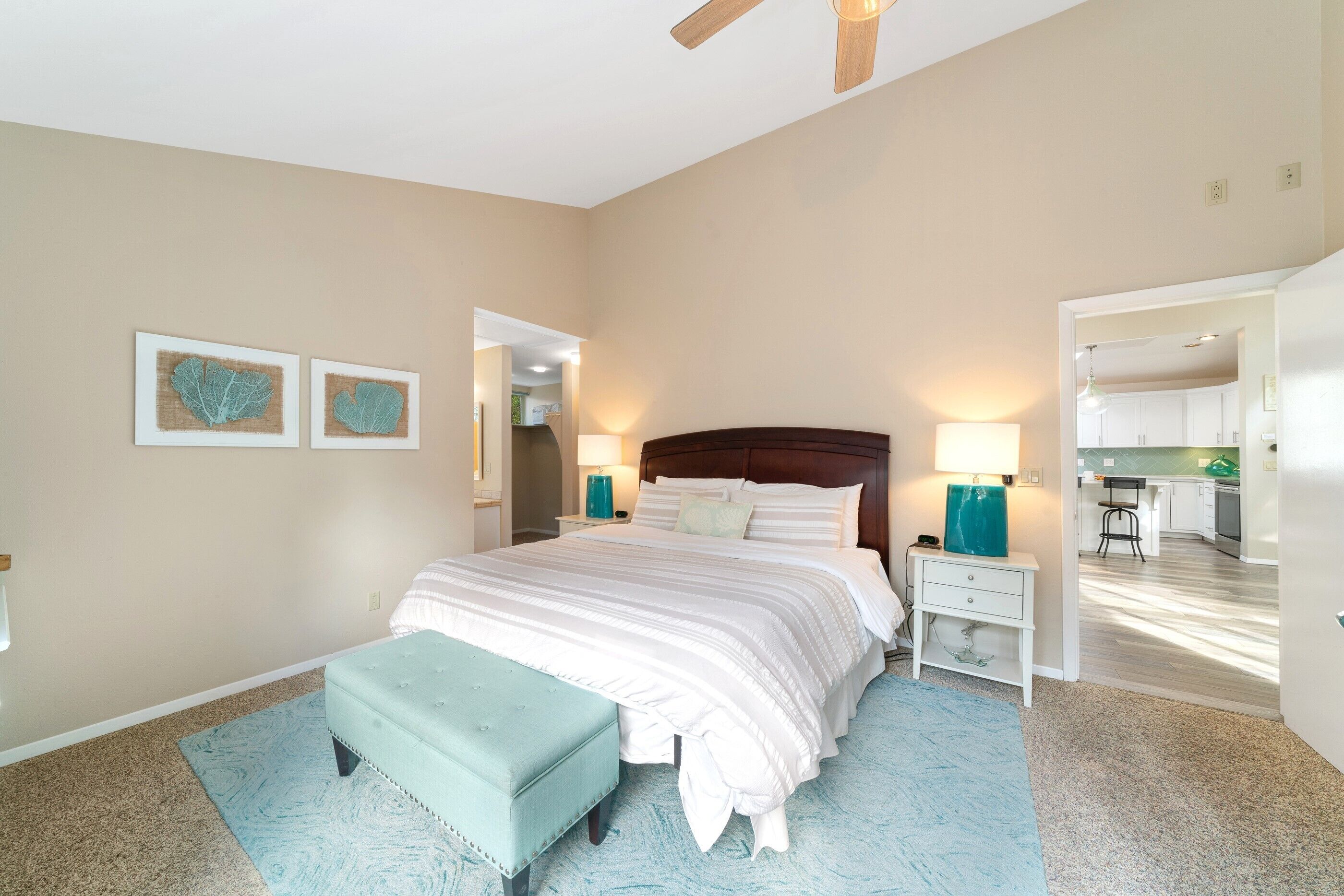 A bedroom with a large bed, a nightstand, a bench, and a wall-mounted mirror.
