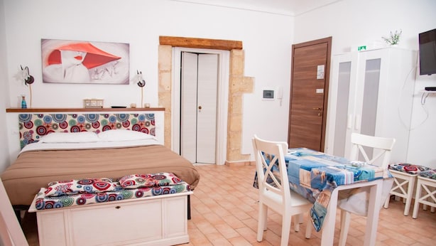 Een slaapkamer met een bed, een houten hoofdeinde, een nachtkastje, een stoel, een tafel met tafelkleed, een kledingkast en een televisie.