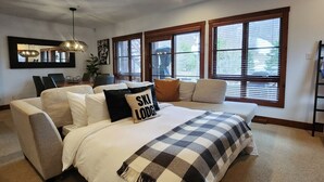A bedroom with a large bed, a sofa, a dining table, and a chandelier. - Tremblant Prestige - Étoile 1510-4 (Mont-Tremblant)