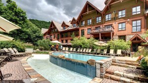 A pool area with lounge chairs and a wooden building with balconies. - Tremblant Prestige - Étoile 1510-4 (Mont-Tremblant)