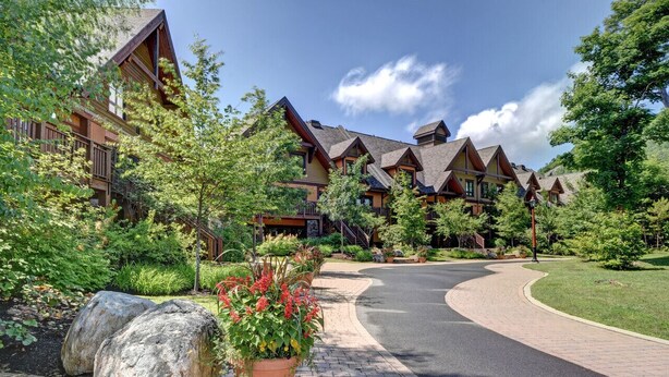 A lodge with multiple wooden cabins, a paved driveway, and surrounding greenery. - Tremblant Prestige - Étoile 1510-4 (Mont-Tremblant)