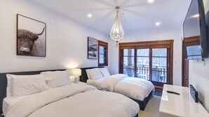 A hotel room with two beds, a chandelier, a TV, and a window with a view. - Tremblant Prestige - Étoile 1510-4 (Mont-Tremblant)
