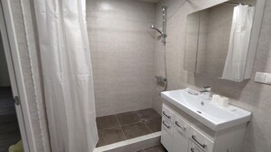 A bathroom with a shower, a sink, and a mirror. - Cozy Airport Guesthouse - Woolway Studios (Argavand,)