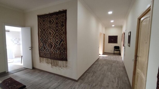A hallway with patterned wall hanging, a door, and a chair. - Cozy Airport Guesthouse - Woolway Studios (Argavand,)
