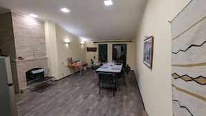 A dining area with a brick fireplace, a table with chairs, and a patterned wall. - Cozy Airport Guesthouse - Woolway Studios (Argavand,)
