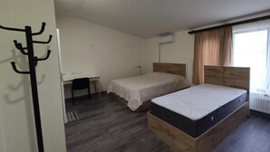 A room with two beds, a desk, and a chair. - Cozy Airport Guesthouse - Woolway Studios (Argavand,)