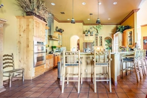 A spacious kitchen with wooden cabinets, a central island with chairs, and a tiled floor. - Near Lion Country Safari! Large Family-sized home (Loxahatchee)