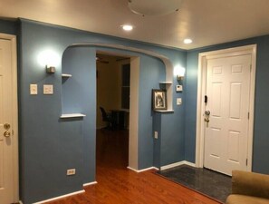 A hallway with blue walls, a white door, and a wooden floor. - Charming, cheerful, comfortable, centrally located, and walkable!
(Pittsburgh)
