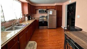 A kitchen with wooden cabinets, stainless steel appliances, a sink, and a dining area with a table. - Charming, cheerful, comfortable, centrally located, and walkable!


 (Pittsburgh)