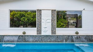 A building with a pool, a decorative face sculpture, and a tiled wall. - Perfect Urban Escape: Your Personal Oasis with a Zen Den and Lush Gardens! (Delray Beach)