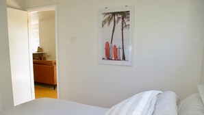 A bedroom with a bed, a striped pillow, and a framed picture of surfboards on the wall. - WERRI North.
 (Werri Beach)