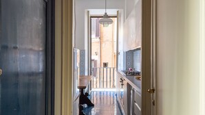 Un pasillo estrecho con un banco de madera, una puerta y vistas a una habitación con balcón.