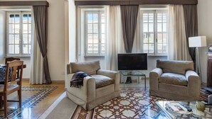 A living room with two armchairs, a TV, and a patterned rug.