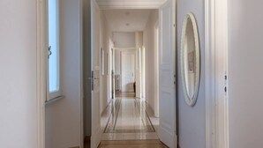 A hallway with a patterned rug, white walls, and doors leading to other rooms.