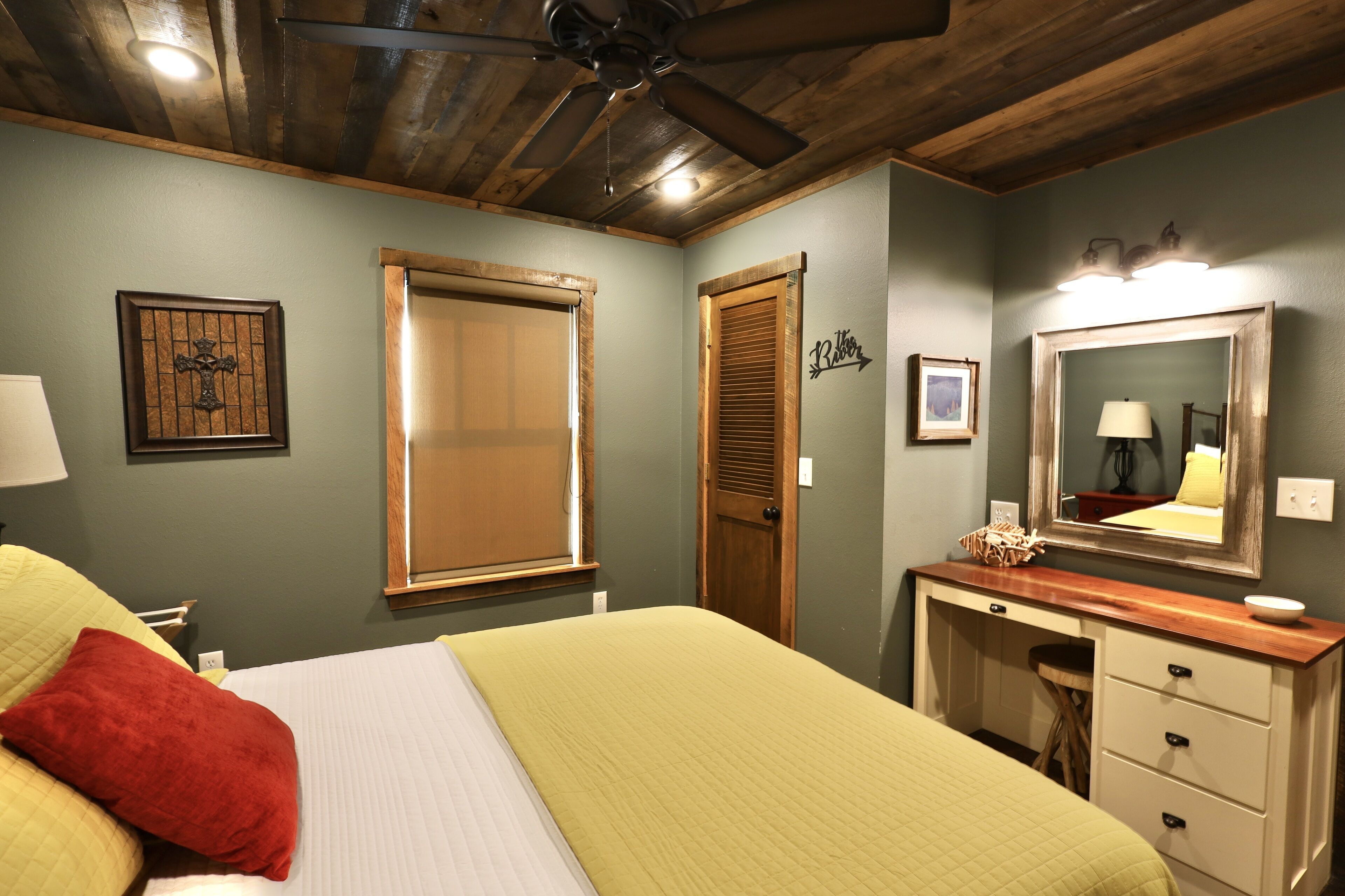 Un dormitorio con cama, mesita de noche, cómoda, espejo y ventilador de techo.