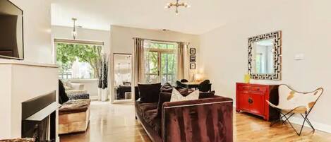 A spacious living room with a dark-colored sofa, a red cabinet, and a large mirror on the wall.