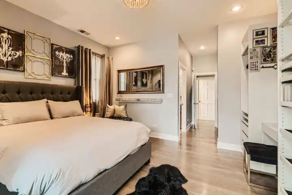 A spacious bedroom with a large bed, a chandelier, and a mirror above the bed.