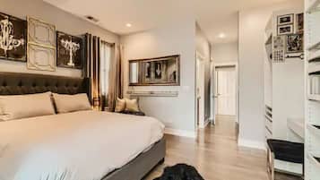 A spacious bedroom with a large bed, a chandelier, and a mirror above the bed.