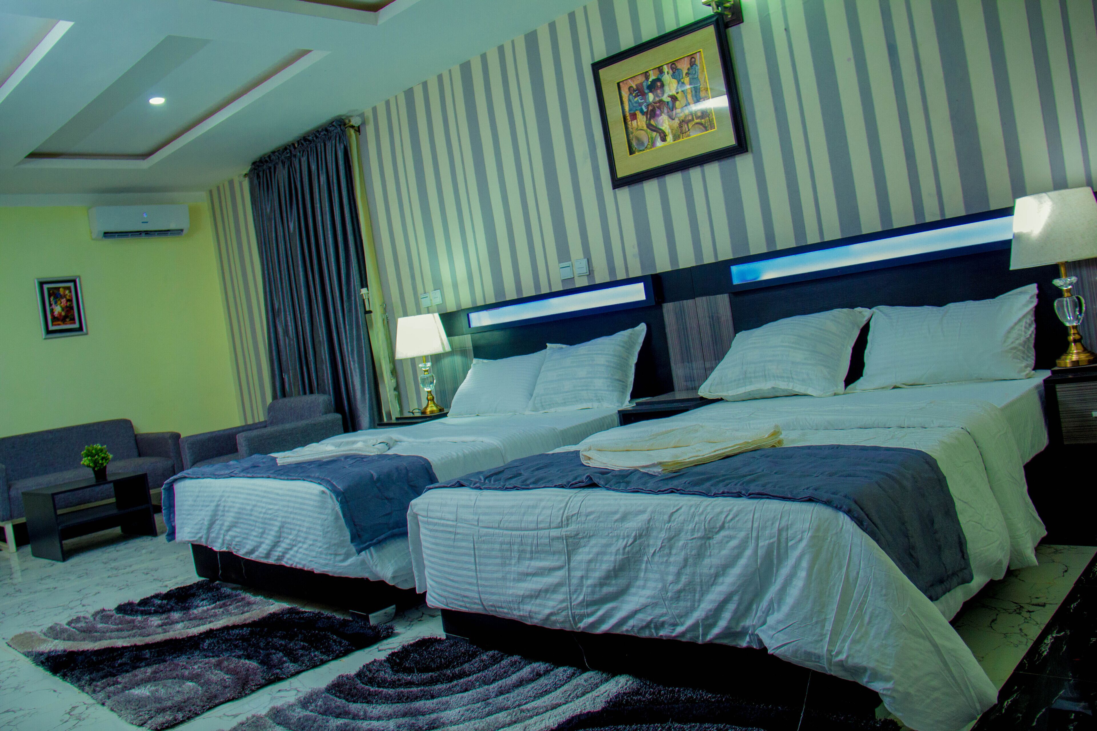 A hotel room with two beds, a sofa, a small table, and a lamp.