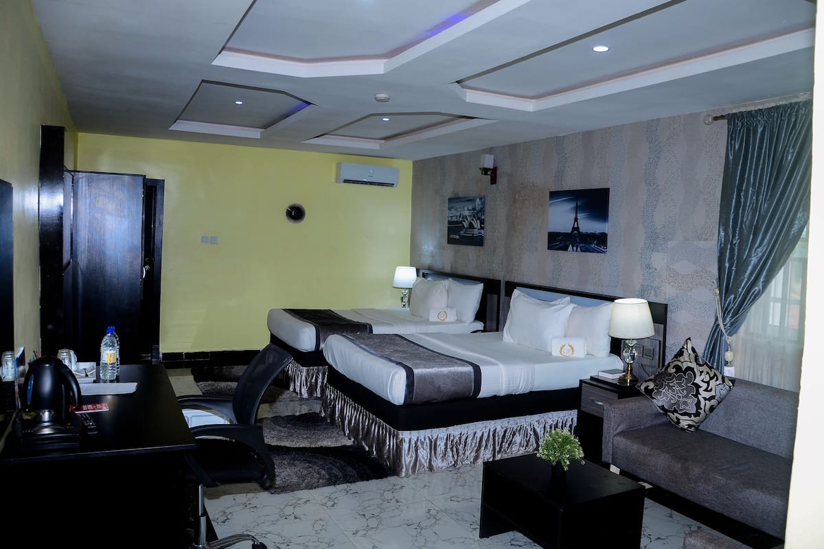 A hotel room with a large bed, a sofa, a desk, and a TV.
