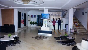 A hotel lobby with a reception desk, seating area, and a staircase. - GPinnacle Suites (Ilorin)