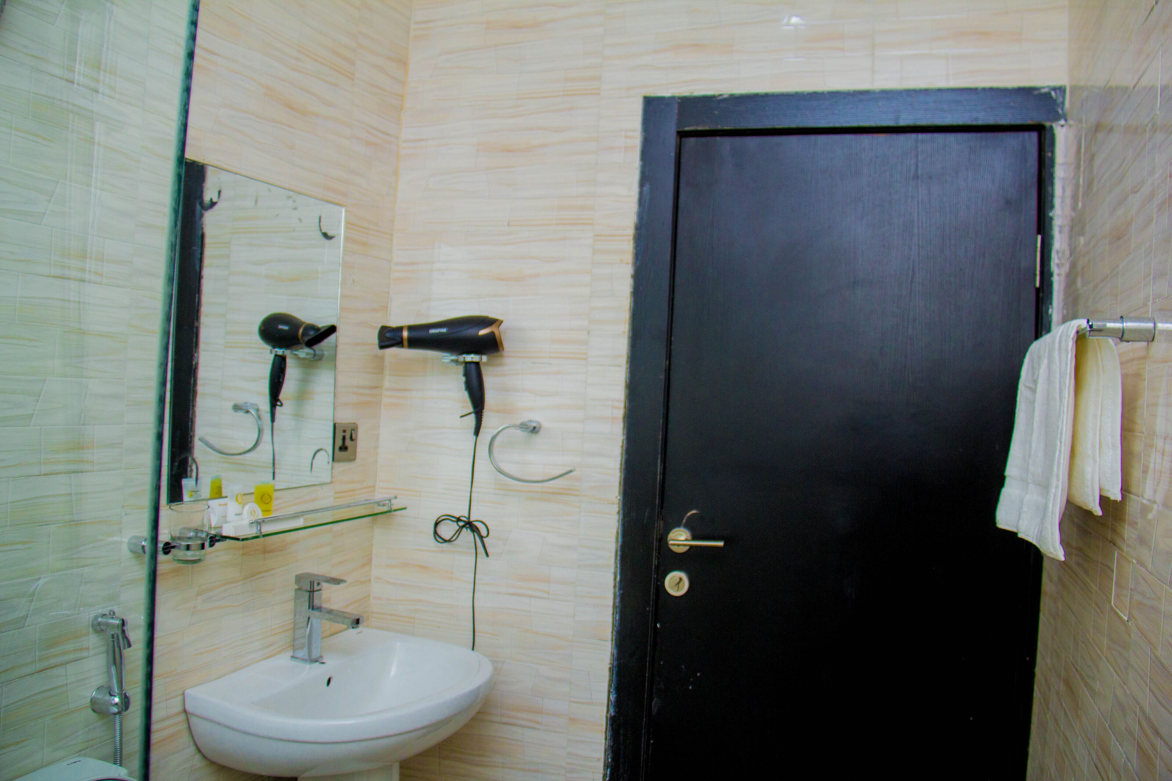 A bathroom with a white sink, a mirror, a hairdryer, and a towel rack.