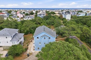 A residential area with houses, trees, and a view of the ocean. - 1712 - Happy Childhood, Corolla Coastal Home | Pool, Hot Tub & Game Room (Corolla)