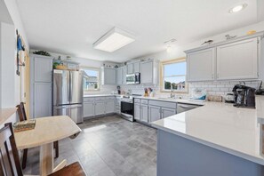Una cocina moderna con armarios blancos, un refrigerador de acero inoxidable, un horno empotrado y una isla grande con pileta.