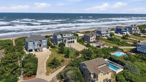 Un quartier résidentiel situé sur la côte, avec des maisons, une piscine et une vue sur la plage.