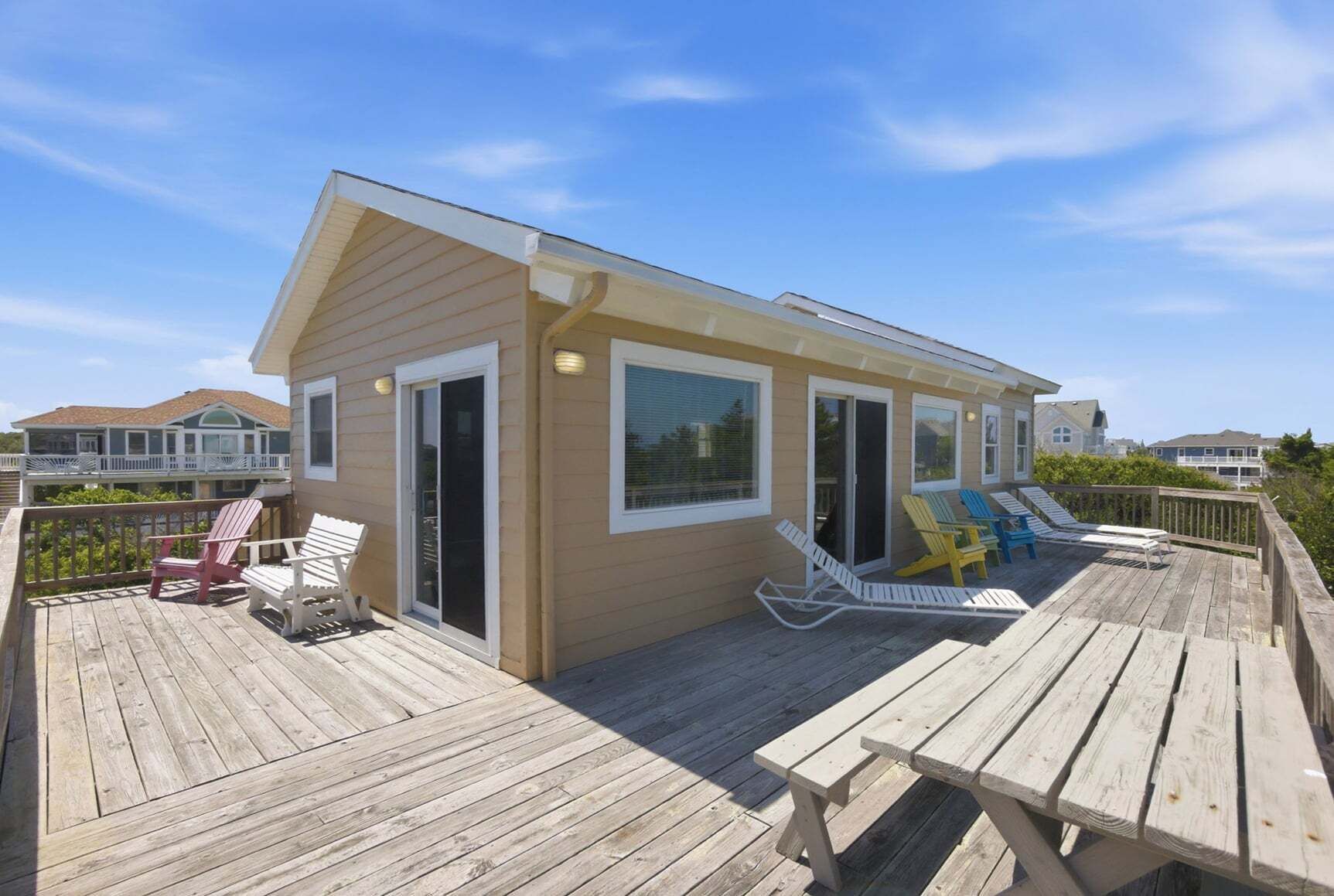 Une maison de plage dotée d’une terrasse, de meubles d’extérieur et offrant une vue sur l’océan.