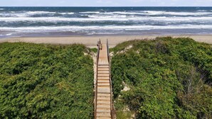 Une promenade en bois menant à une plage avec vue sur l’océan.