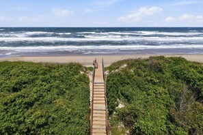 A wooden boardwalk leading to a beach with ocean views.