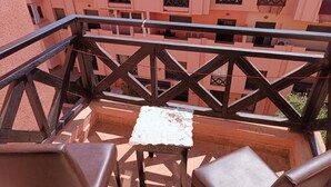 A balcony with a table and chairs, a railing, and a building in the background. - Un Joli Appartement Premium 23 (Marrakech)