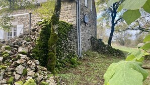 A stone building with a moss-covered exterior, a visible door, and a small window. - Magnifique Propriété sur un Terrain de 55 Ares, Piscine, 5 Chambres (Orniac)