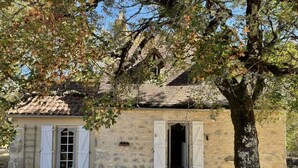 A rustic stone building with a tiled roof, two white doors, and a small porch. - Magnifique Propriété sur un Terrain de 55 Ares, Piscine, 5 Chambres (Orniac)